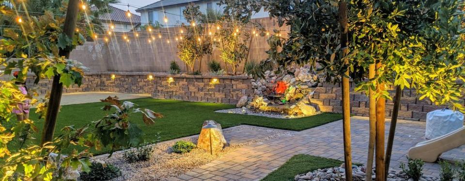 Beautifully designed backyard landscape. All features are well lit and there are hanging lights.